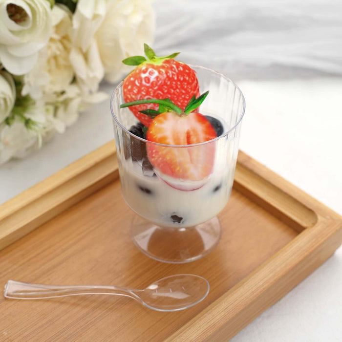 Yogurt parfait with strawberries and blueberries in a clear cup on a wooden tray.