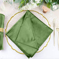 Green velvet napkin on elegant table setting with gold accents and floral decor.