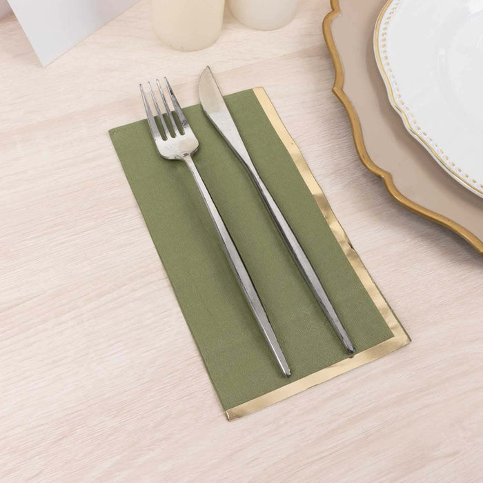 Silver fork and knife on a green napkin with gold trim.