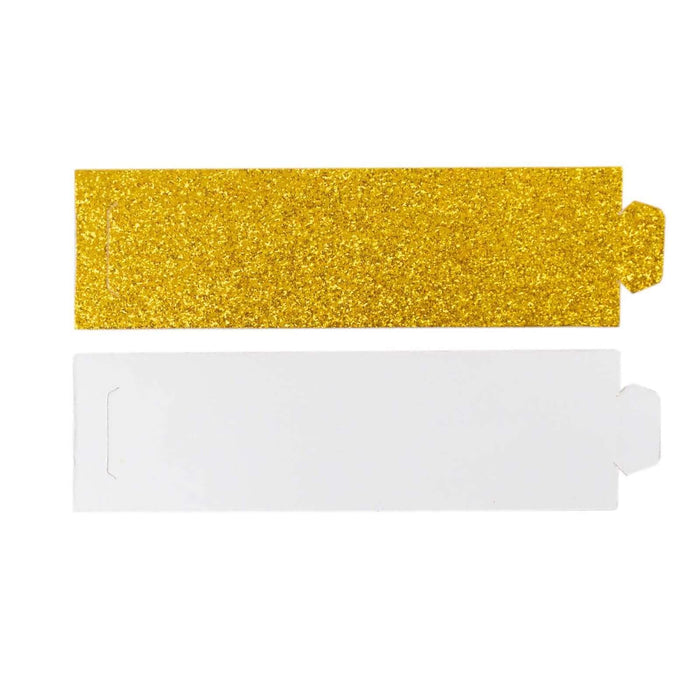 Gold glitter and white cardstock cutouts on a plain background
