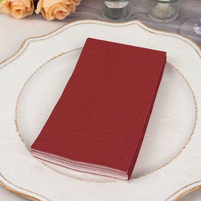 Burgundy napkins stacked on a decorative plate.
