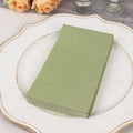 Green paper napkins stacked on a decorative plate.