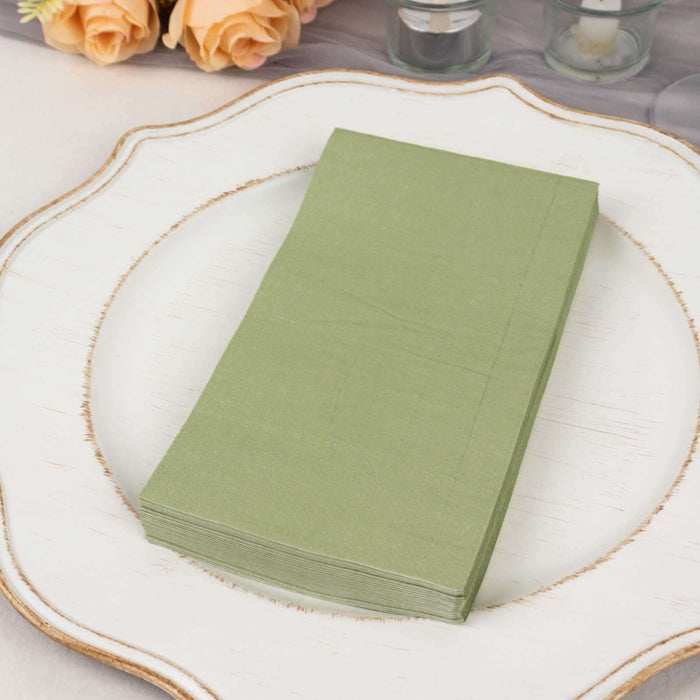 Green paper napkins stacked on a decorative plate.