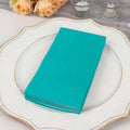 Stack of teal napkins on a decorative plate.