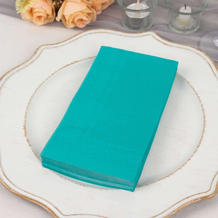 Stack of teal napkins on a decorative plate.