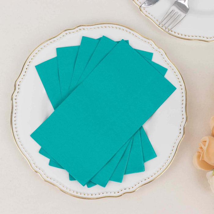 Teal paper napkins stacked on an elegant plate.