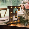 Decorative marquee letter 'E' with lights on a rustic table setting.
