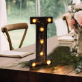 Decorative marquee letter "I" with lights on a rustic table setting.