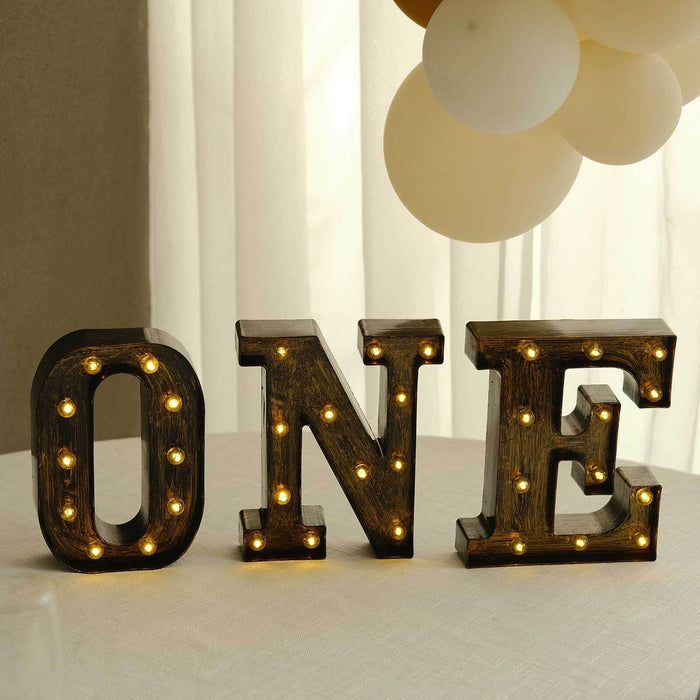 Illuminated marquee letters spelling "ONE" on a table.