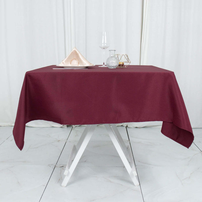 Elegant burgundy tablecloth draped over a white table with dining accessories.