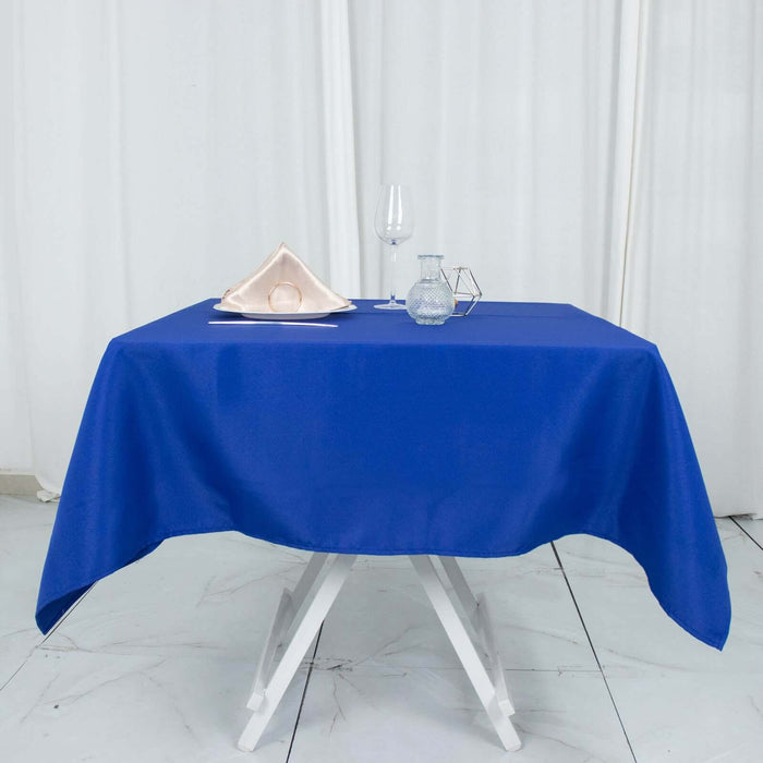 Blue tablecloth on a white table with glassware and napkin setup.