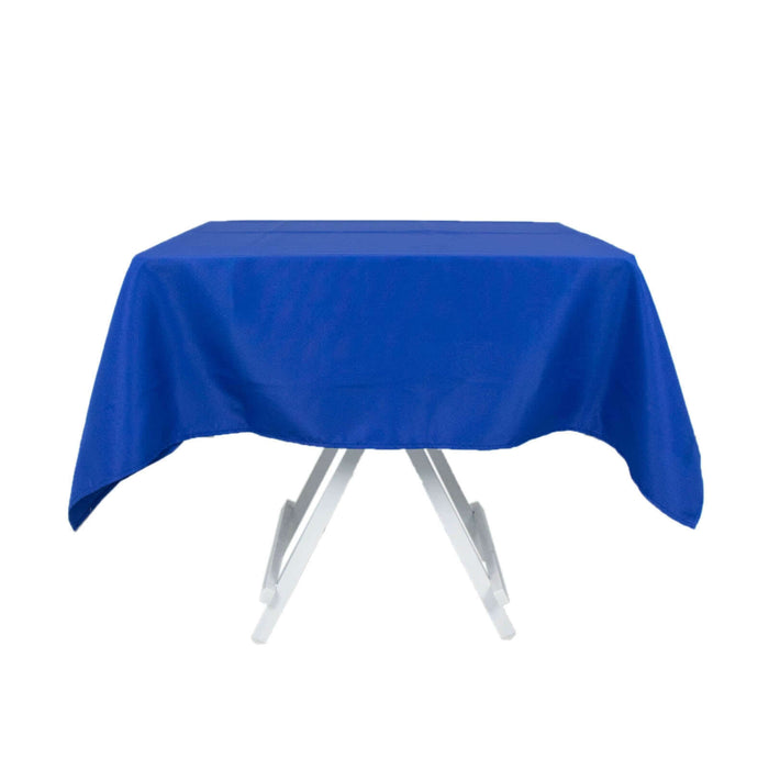 Blue tablecloth draped over a folding table on a plain backdrop