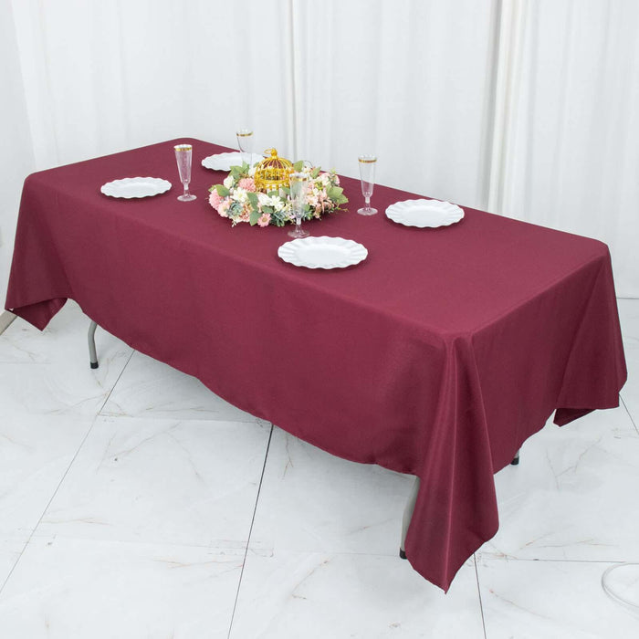 Maroon tablecloth on a dining table set with plates and floral centerpiece.