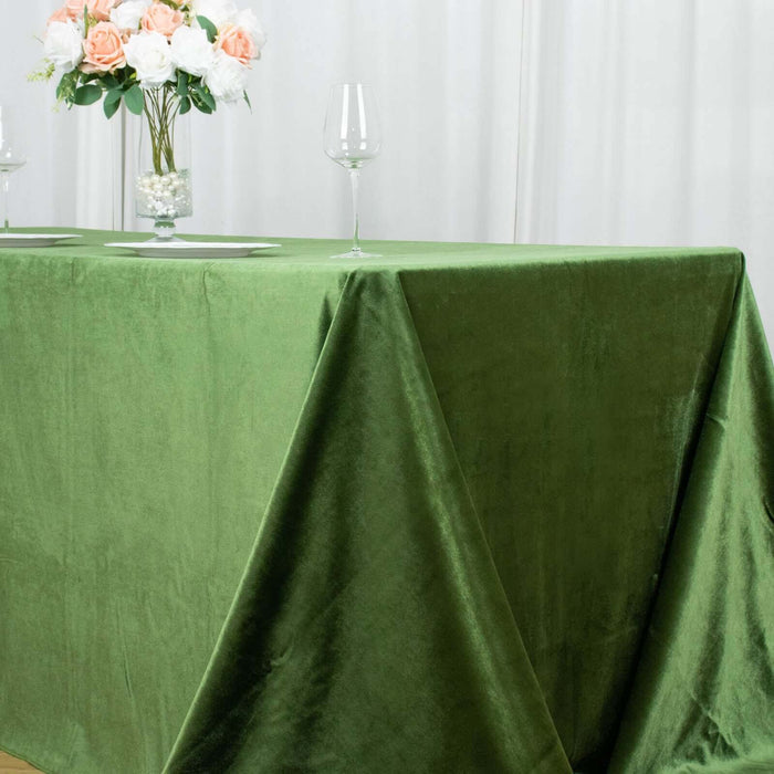 Green velvet tablecloth draped elegantly on a table with a floral centerpiece.