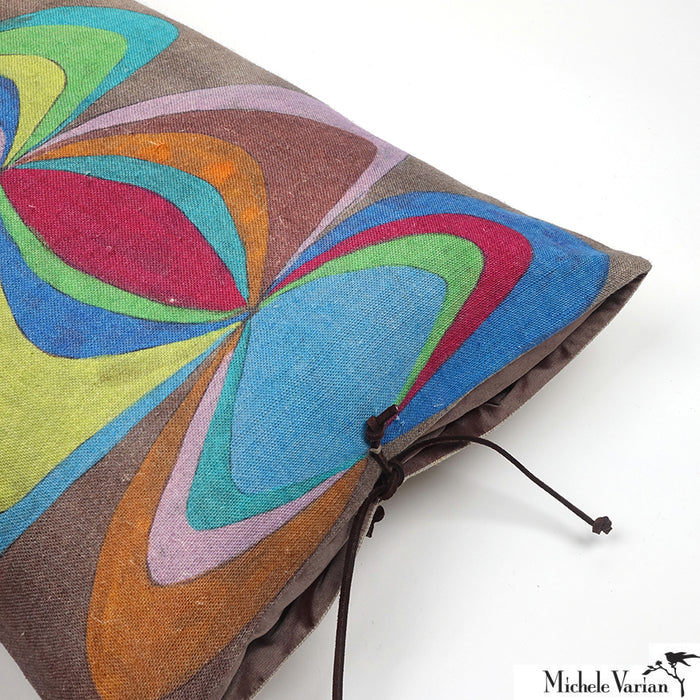 The top corner of a linen throw pillow with a colorful geometric pattern and a leather tie closure.