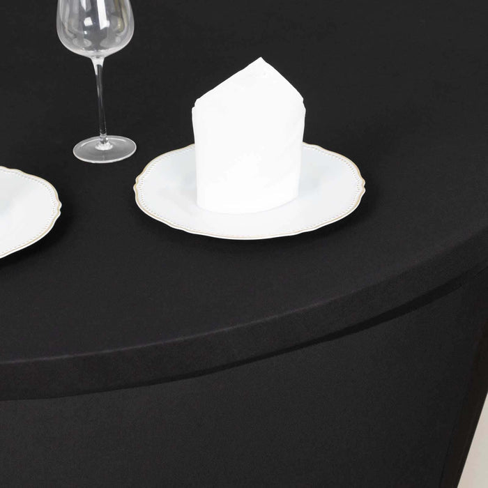 Elegant table setting with a white plate and napkin on a black tablecloth.