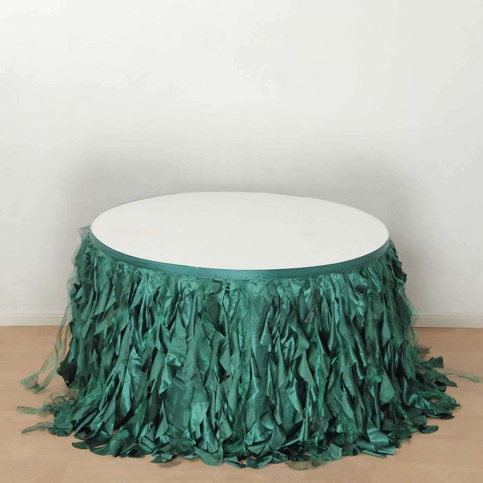 Round table with green fringe skirt on a plain white background